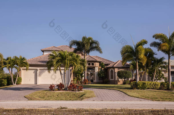 典型的西南佛罗里达混凝土砌块和灰泥回家与棕榈树、 热带植物和花卉，农村草草坪和松树。佛罗里达州