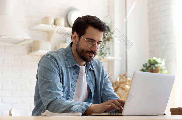 专注的年轻人，戴着眼镜，使用笔记本电脑，键盘打字