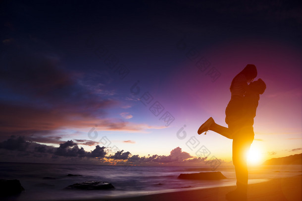落日下的剪影的年轻夫妇在<strong>爱</strong>拥抱在海滩上