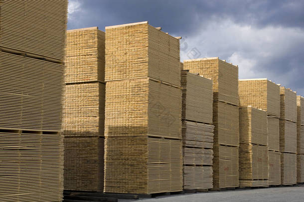  木材工业-成品木材对天空。成堆的加工木板