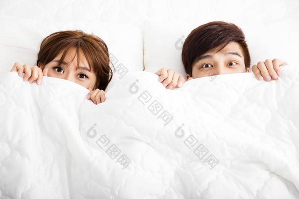 惊讶的年轻夫妇，躺在床上