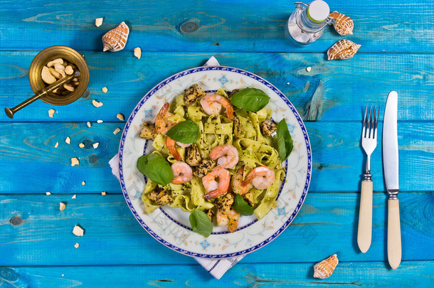 Tagliatelle pasta with shrimps, nuts and chicken on wooden table