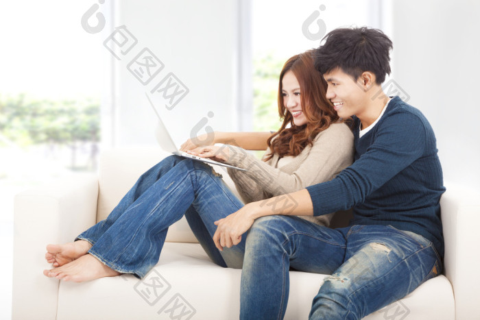 夫妇在沙发上用笔记本电脑的图片-包图网企业站