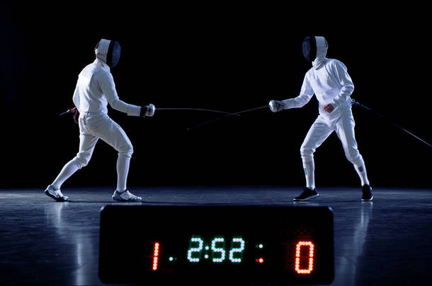冠军两个专业充分装备击剑与战斗<strong>在</strong>箔计分板保持同时命中的成绩。拍摄于孤立的黑色背景.