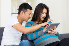 亚洲孕妇和她的丈夫使用平板电脑