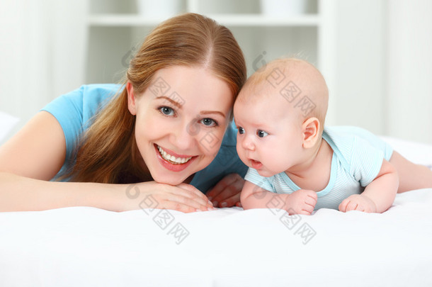 快乐家庭的母亲和婴儿在床上玩