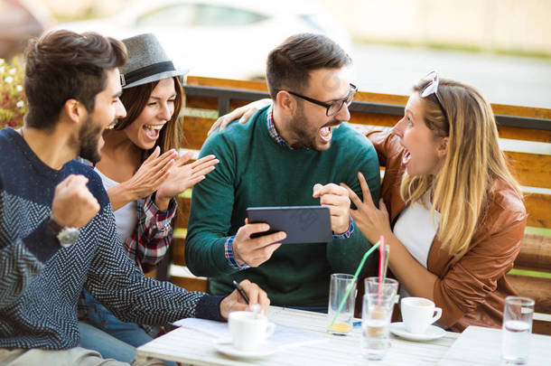 四组朋友一起喝咖啡。两个女人和两个男人在咖啡馆说笑, 享受他们的时间使用数字<strong>平板电脑</strong>.