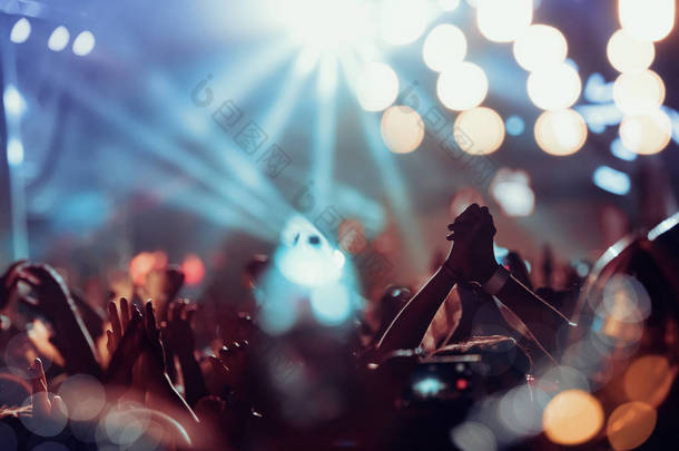 <strong>音乐</strong>会上的人群。在五颜六色的舞台灯光前欢呼的人群.