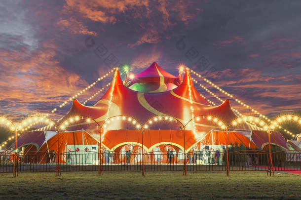 Night view of a circus tent under a warn sunset and chaotic sky