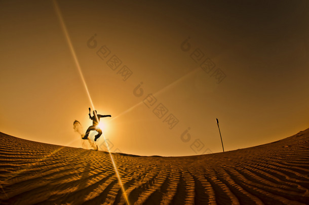 男人在手与箭头跳、 迪拜沙漠、 阿拉伯联合酋长国的剪影