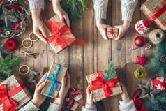 圣诞快乐,节日快乐!一个母亲、父亲和女儿在准备礼物。包，礼物，糖果和装饰品顶部视图。圣诞节家庭传统.
