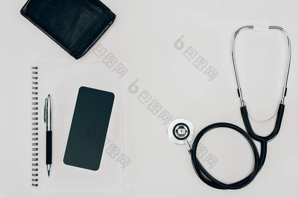 医用听诊器、笔记本和智能手机在白色表面的顶部视图