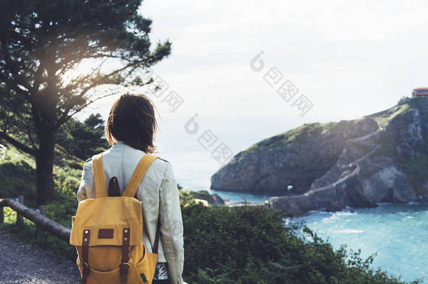 时髦少女享受海景峰山上的日落，<strong>背包</strong>里。旅游旅行上背景谷景观视图样机。<strong>徒步</strong>旅行者在巴斯克人岛旅行假期看阳光海洋 