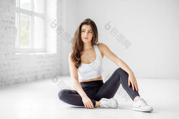 一个年轻女孩坐在健身房的地板上。运动理念,健康的生活方式,健身,<strong>伸展</strong>.