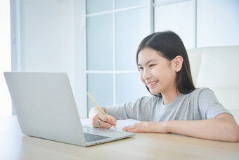 十几岁以下的亚洲女学生在家里带着笔记本电脑上网学习。儿童的教育和远距离学习。检疫期间的家教. 图片