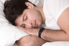男子睡在床上穿睡眠跟踪智能腕带
