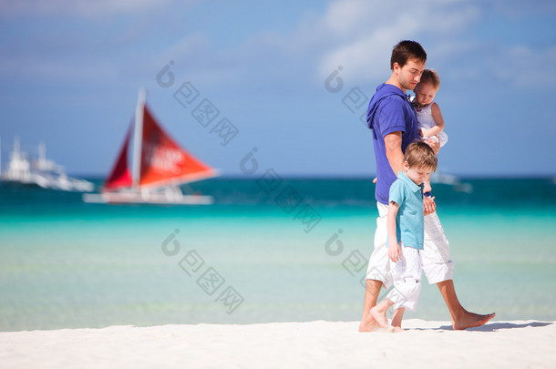 父亲<strong>和</strong>两个孩子在沙滩散步