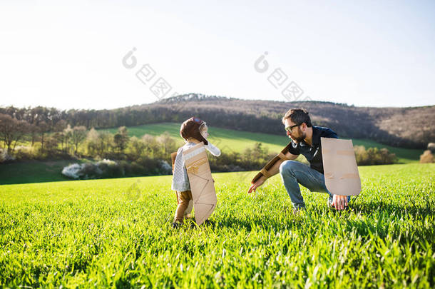 快乐的蹒跚学步的男孩与父亲在春天自然外面玩耍.