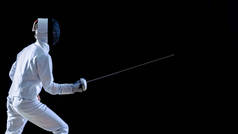 齐全的熟练击剑训练他的攻击和弓步侧视图与箔。孤立在黑色背景上的镜头.