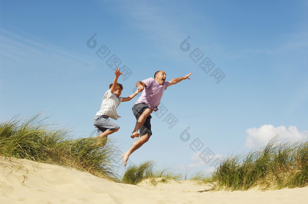 父亲和儿子在海滩上跳跃