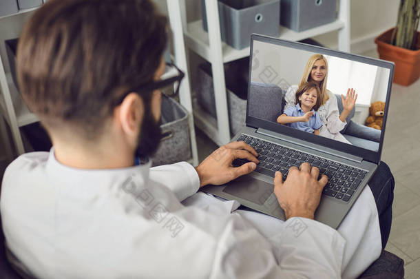 医生在诊所的办公室里使用电脑摄像头为有小孩的妇女提供咨询.
