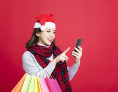 幸福的女人买圣诞礼物的智能手机