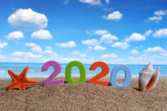 2020号和海贝壳与海星在沙滩上。新年快乐和暑假概念.