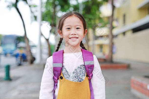 <strong>快乐的</strong>亚洲<strong>女孩</strong>行走与学生肩书包。小女生，有背包前视图。回到学校概念.