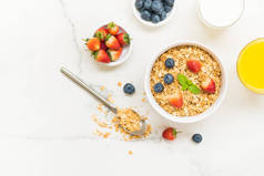 健康早餐在白色石桌背景设置燕麦饼与蓝莓和草莓和黑咖啡、牛奶和橙汁