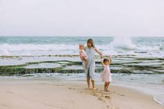 年轻的母亲与可爱的小女儿放松在沙滩海滩