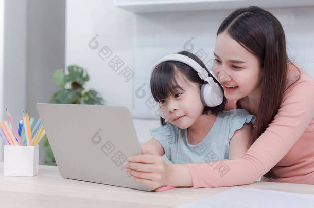 【参考译文】亚洲的母亲和女孩们通过互联网<strong>学习</strong>使用笔记本<strong>电脑</strong>听耳机发出的声音