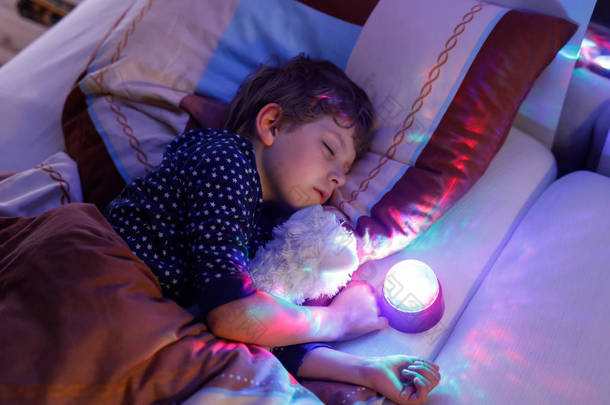用彩色灯在<strong>床</strong>上睡觉的小学龄前孩子男孩.