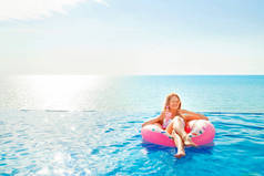 暑假。在充气的甜甜圈床垫在水疗中心的游泳池里的比基尼的女人.
