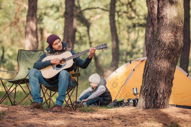 父亲和儿子一起在森林里的吉他