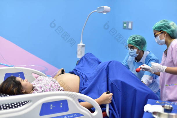 医生和护士正在进行盆腔手术。给在医院生孩子的女人.
