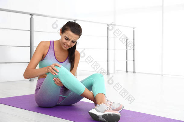 穿着运动服的年轻女子在健身房有膝盖问题。文本空间