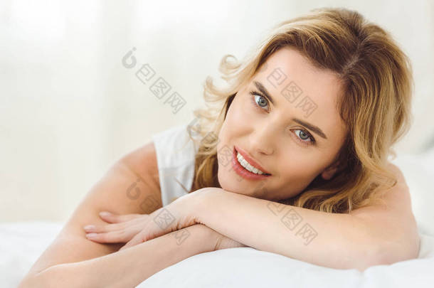 美丽的微笑的女人躺在床上在家 