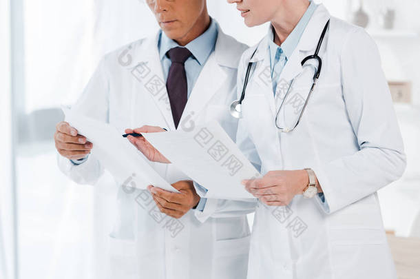 医生在诊所拿着空白纸的裁剪视图 