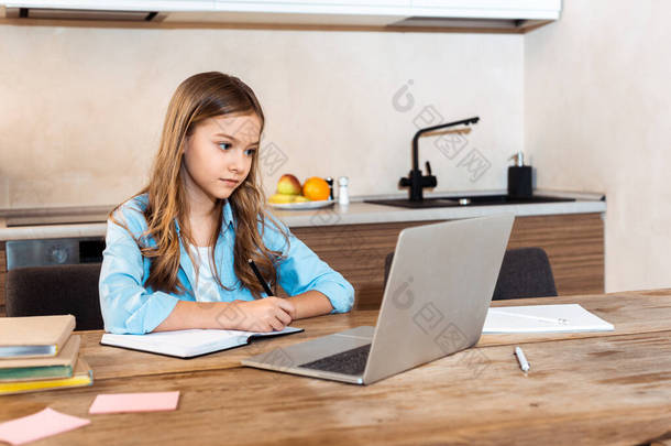 在家里进行电子学习的同时，有选择地关注可爱的孩子在<strong>笔记本电脑</strong>旁写作的问题