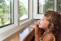 漂亮微笑着阳台上的小女孩，从窗口看