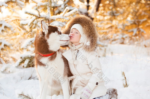 快乐的小金发女孩在开心地和她在雪中的大狗