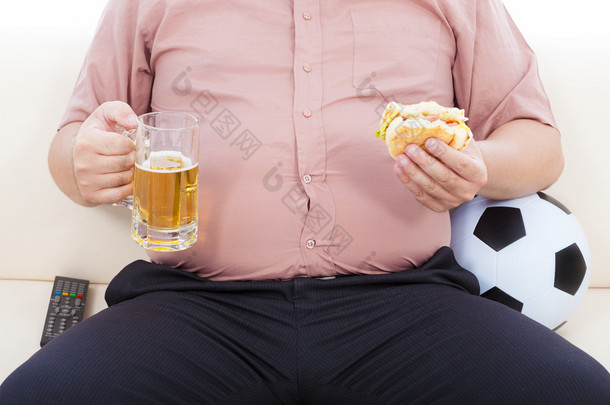胖商<strong>人</strong>吃食物和啤酒，坐在沙发上