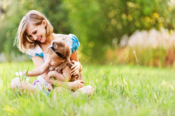 young mother and daughter relaxing on grass