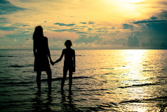 母亲和女儿海滩上散步，清晨的时候