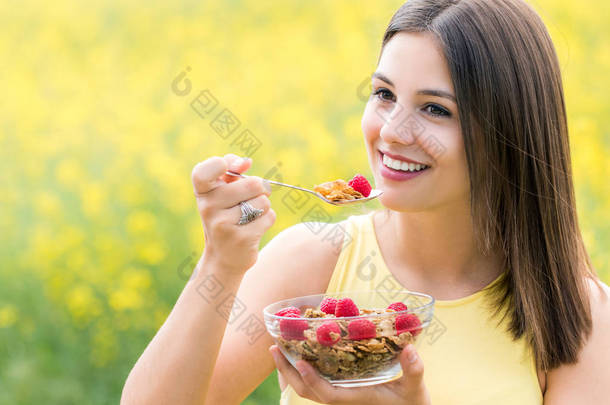 可爱的年轻女子在户外吃健康谷物.