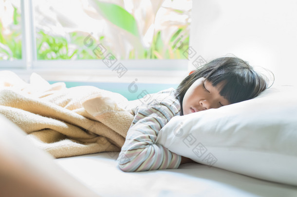 亚洲女孩睡在床上盖上条毯子.