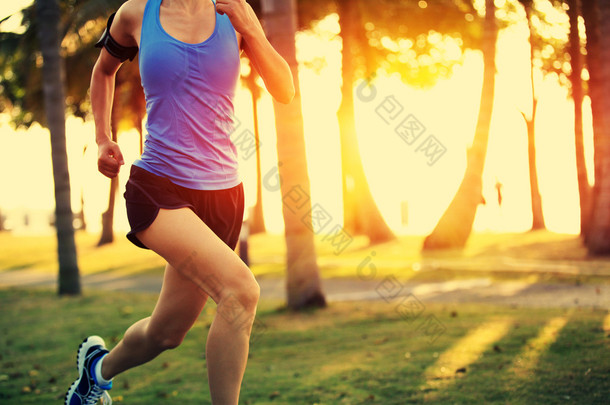 在热带公园运行的跑步运动员。女人健身日出慢跑锻炼健康概念.