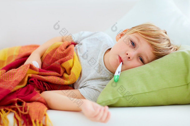 生病的孩子，与流鼻涕的鼻子和发烧热，躺<strong>在家</strong>里的沙发上