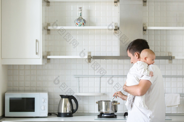 男人在厨房里牵着一个小孩子，在肩上，做饭