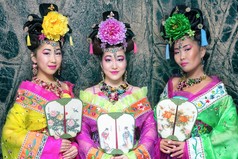 三个美丽的中国女人，在传统中国服饰与风扇附近大理石墙